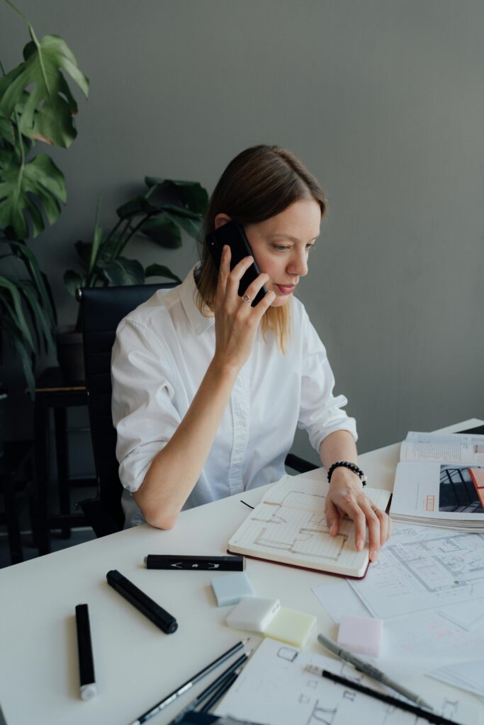 Focused woman architect discussing floor plans on the phone in an office setting.